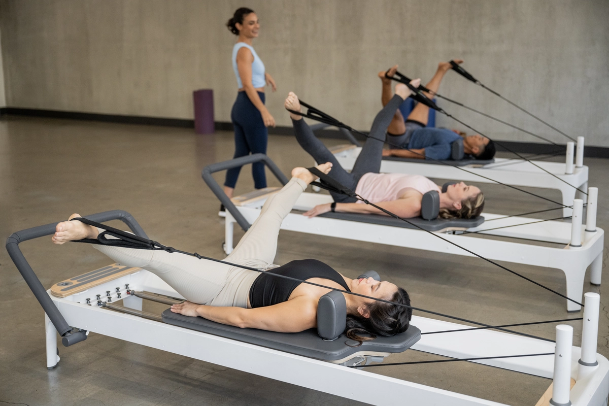 Gruppo di persone a lezione di pilates con reformer